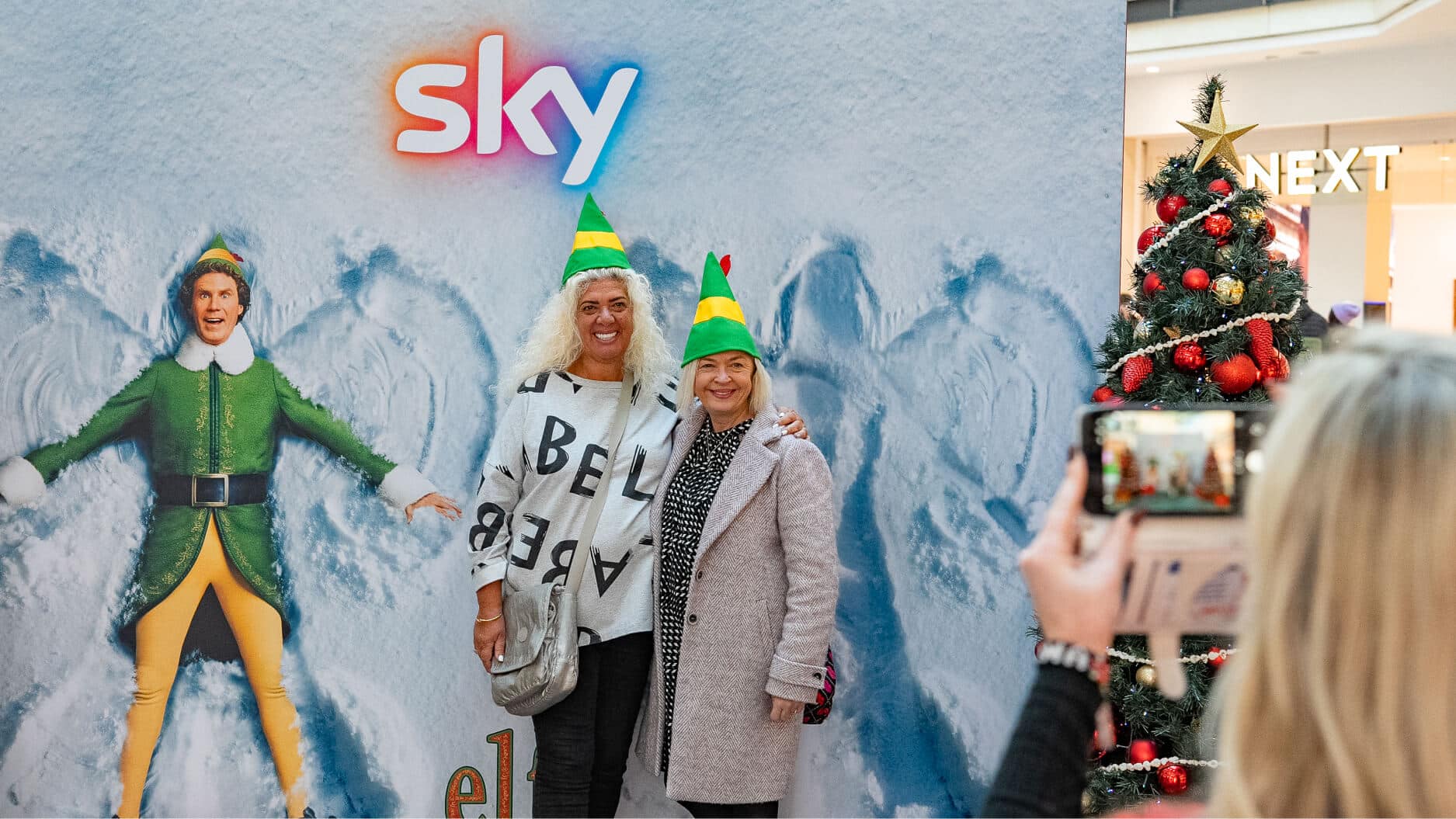 Two people posing with holiday decorations.