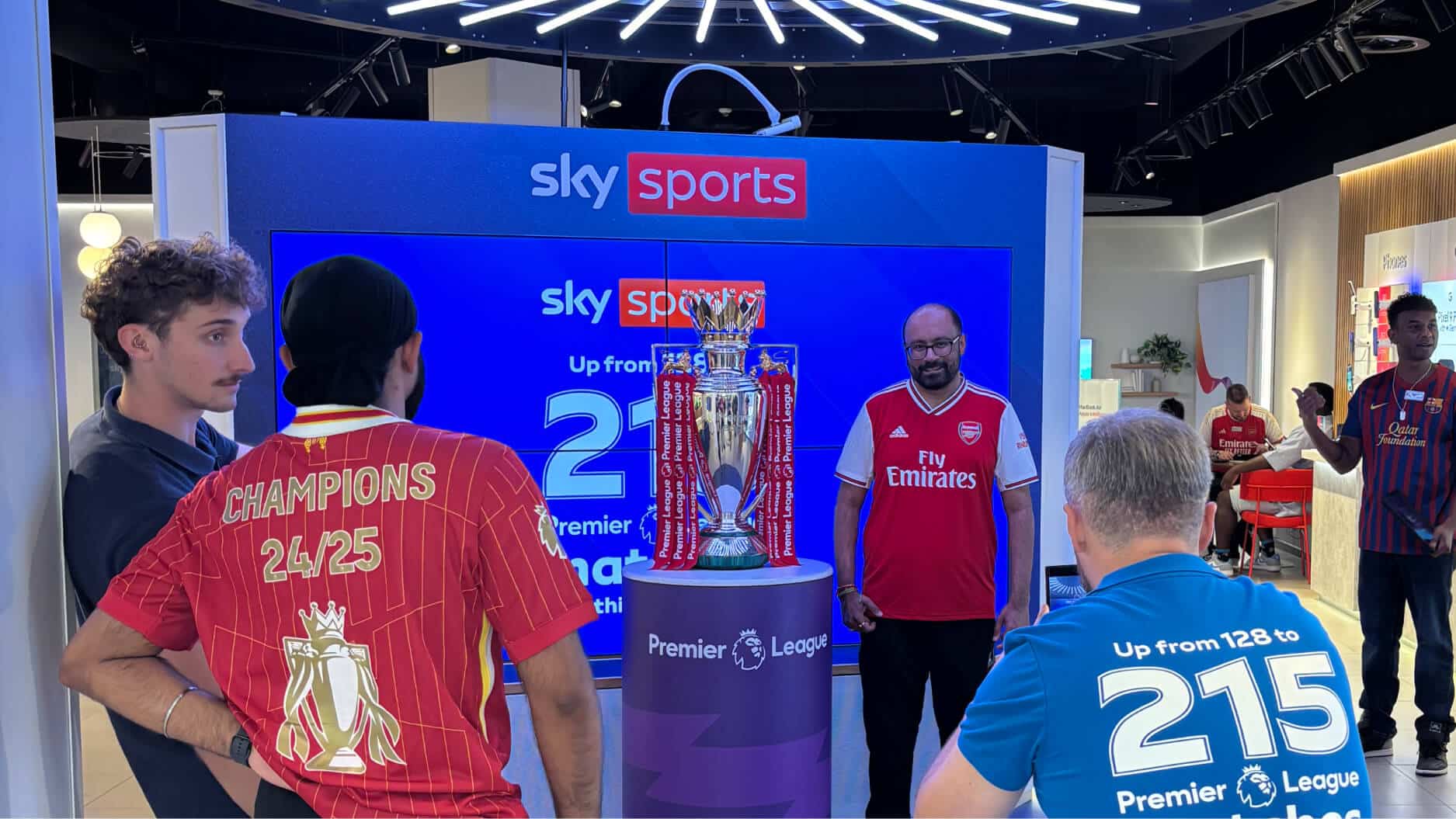 People admiring a football trophy.